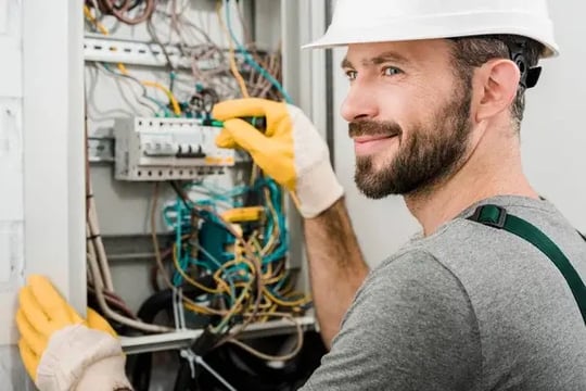 stock-photo-handsome-cheerful-electrician-repairing-electrical-box-using-screwdriver-corridor